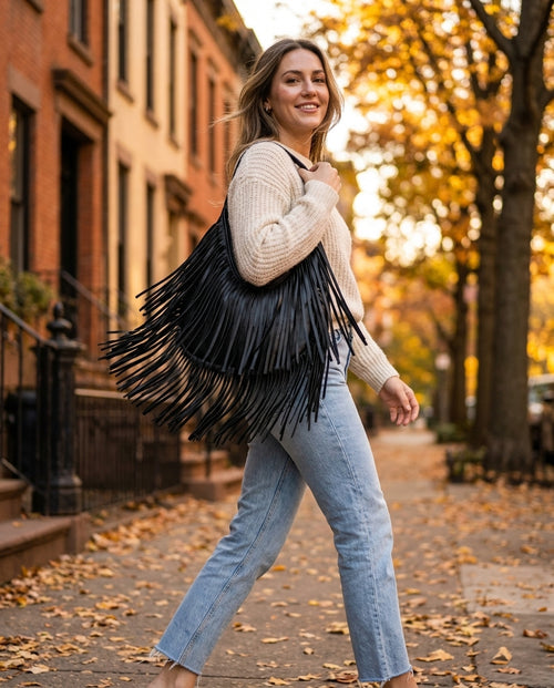 Woman walking down a fall street carrying the black Fringe Hobo on her shoulder, fringe mid-swing